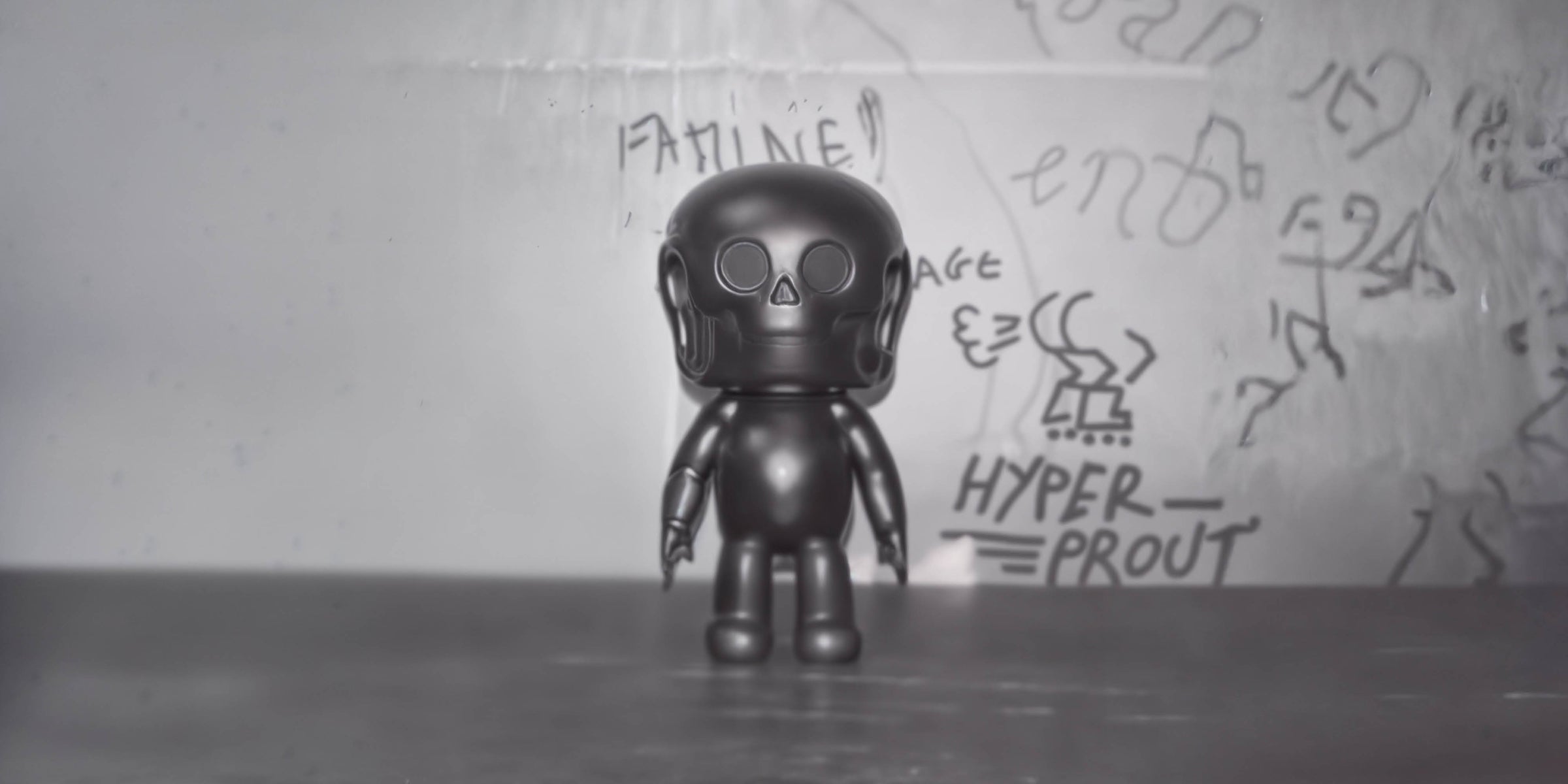 Pièce NOTOY noire devant un mur couvert de graffitis